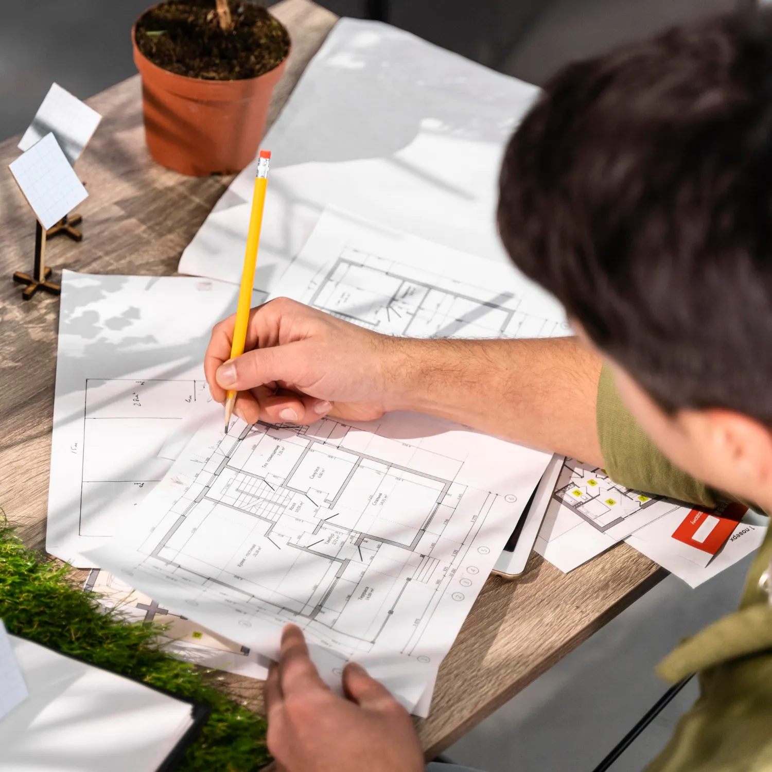 high angle of man working on an eco friendly wind power project with papers and pencil